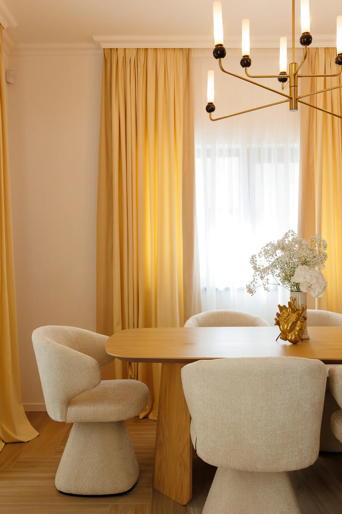 Dining cu draperii aurii, candelabru sculptural și finisaje calde din lemn